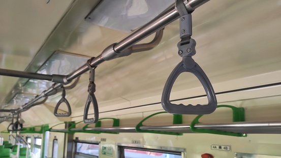 Gray handle grip hanged on the stainless steel bar of the train for train passengers to holding while they standing in the train