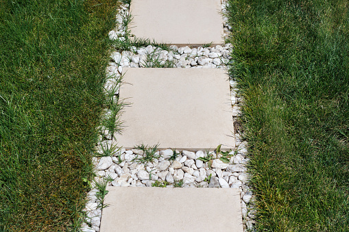 Walkway formed using granite stone slabs in a garden with lush green grass(lawn) on either side