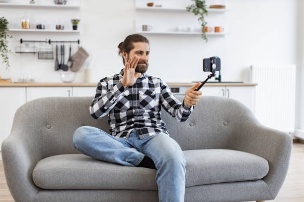 istock bearded adult showing hello gesture while using smartphone with selfie stick 2096204163