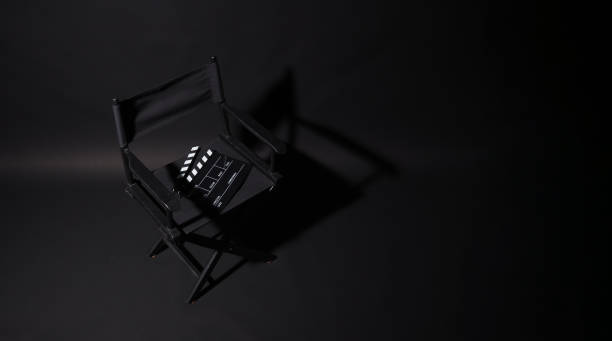 黒い背景に光と影のある黒いディレクターの椅子と拍子木。上面図