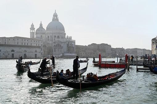 Venice, Italy, march 12, 2024 : Gondoliers with tourists in front of the Basilica San Giorgio Maggiore