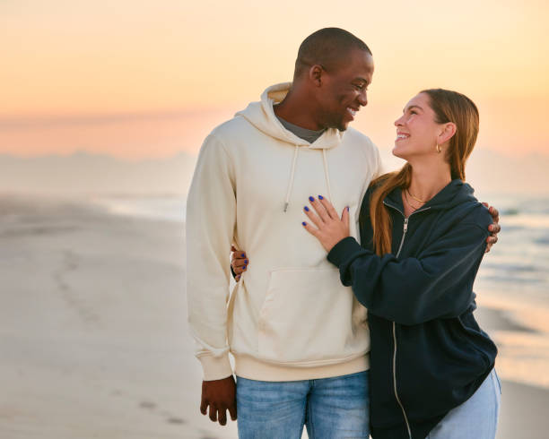 istock Casually Dressed Loving Young Couple Walking Along Beach Shoreline Hugging At Sunrise 2096230435