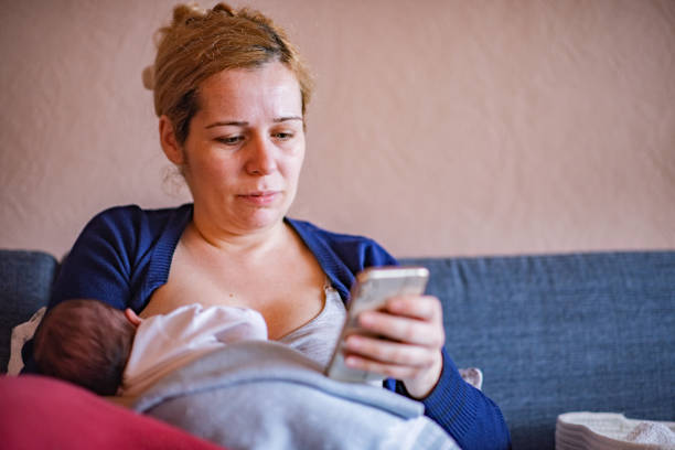 istock Breastfeeding a baby while using phone in living room. 2096249912