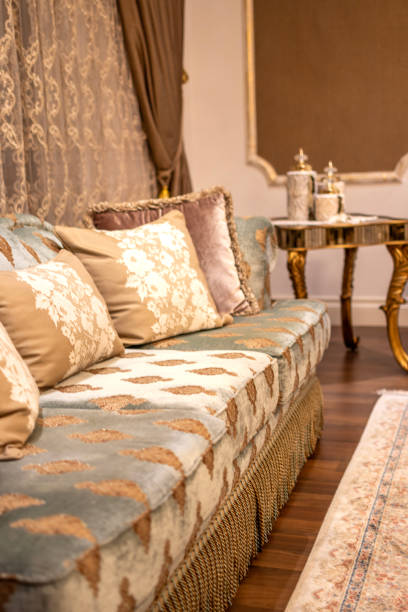 A detailed close-up of a luxurious baroque-style armchair made of green velvet, featuring intricately carved wooden elements and plush cushions