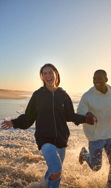 istock Casually Dressed Loving Young Couple Running Along Beach Shoreline Through Waves At Sunrise 2096268904