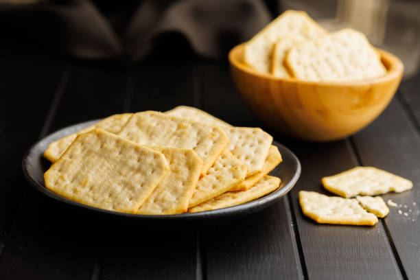 Salted Crackers on a Black Plate Against a Dark Background
