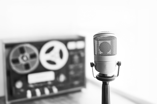 Young smiling woman in with headphones singing in recording studio.