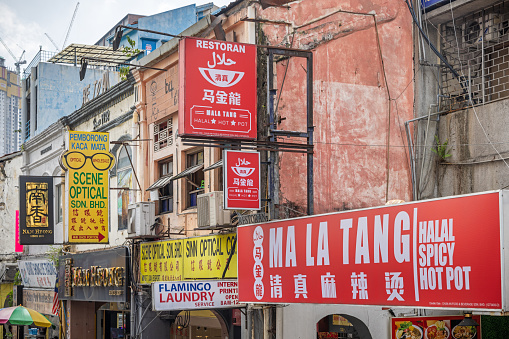 Kuala Lumpur, Malaysia - January 5th 2024:  A selection of advertisement signs seen from a double decker bus in an old street in the center of the Malaysian capital