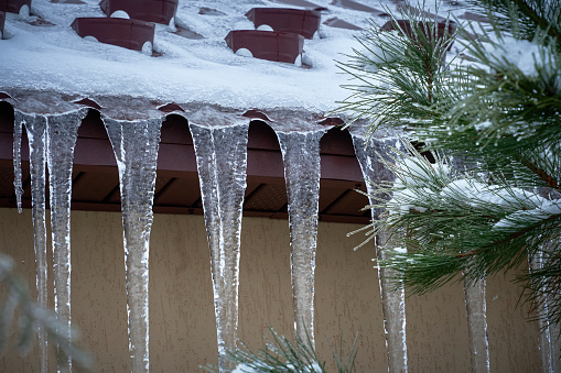 Icicles hang from the roof and from electric wires in early spring in sun rays. Dangerous weather conditions