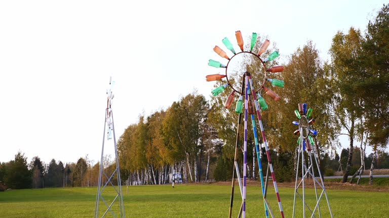 A wind wheel made from old plastic bottles stands on a green lawn and shows the strength of the wind. Using old plastic bottles for household needs. Demonstration of plastic recycling.