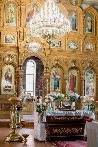 Orthodox church interior with iconostasis and ornate chandelier. Spiritual ambiance for worship, liturgical services. Suitable for religious publications, cultural heritage features