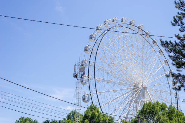 istock Workers on a communication tower by a ferris wheel in white color against summer blue sky 2096388016