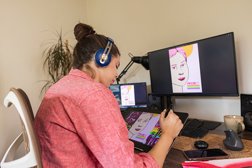 In this stock photo, a Gen Z graphic designer lays the foundation for their business by drawing an illustration for pride.