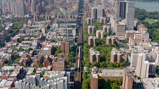 Aerial view of passenger train moving on railway track surrounded by residential buildings in New York City, New York State, USA.