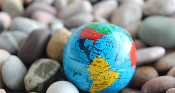 Miniature Globe With A Visible Image Of North and South America On Small Round Sea Rocks