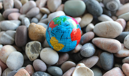 Oceans and continents on a small globe lying on colored pebbles closeup stock photo