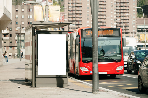 A bus stop in a city with a blank advertisement billboard