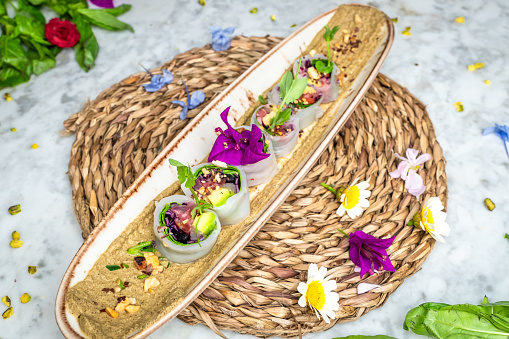 The vegan sushis with avocado on a plate garnished with tiny flowers