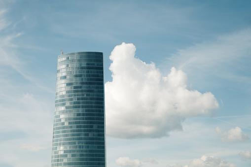 A skyscraper with a cloud behind it