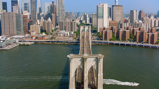 Aerial view of Brooklyn Bridge over East River surrounded by skyscraper buildings, New York City, New York State, USA.