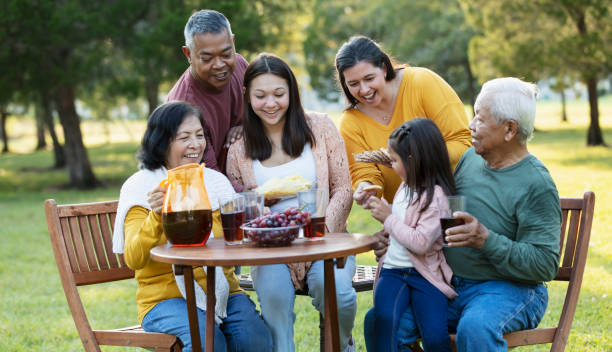 multi-generation multiracial family eating in back yard - filipino ethnicity grandfather senior adult family - fotografias e filmes do acervo