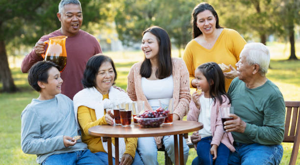 multi-generation multiracial family eating in back yard - filipino ethnicity grandfather senior adult family - fotografias e filmes do acervo