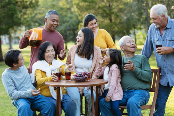 multi-generation multiracial family eating in back yard - filipino ethnicity grandfather senior adult family - fotografias e filmes do acervo