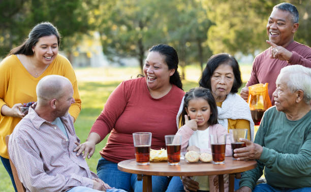 multi-generation multiracial family eating in back yard - filipino ethnicity grandfather senior adult family - fotografias e filmes do acervo