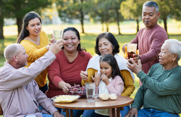 multi-generation multiracial family eating in back yard - filipino ethnicity grandfather senior adult family - fotografias e filmes do acervo