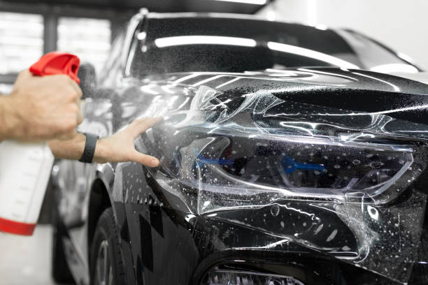 istock Worker applies a protective film or anti-gravity protective coating to the car headlight. Details of the car. 2096425351