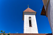 White church tower of catholic church at Slovenian town with blue sky background.