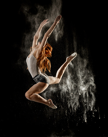 young dancer dancing in flour on black background