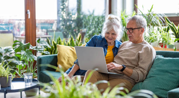 istock Senior couple using laptop while sitting on sofa in living room at home 2096495169