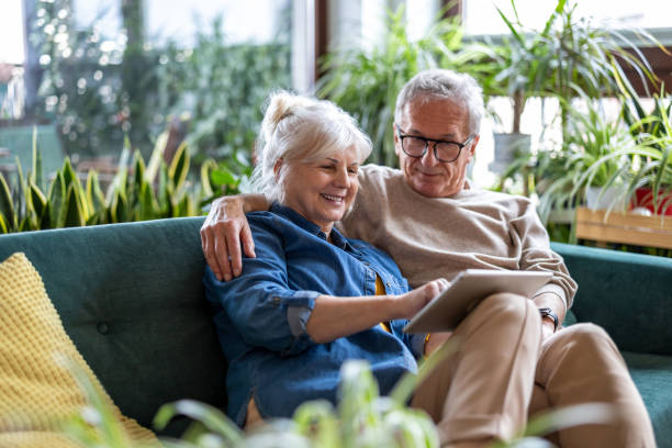 istock Happy senior couple using digital tablet while sitting on sofa in living room 2096495170