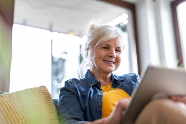 istock Mature woman using digital tablet while sitting on sofa at home 2096495187