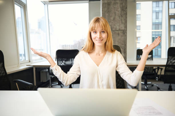 Beautiful joyful woman smiling while working with laptop in office