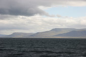 The low slopes of iceland in the distance across the ocean surrounding the island