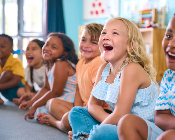 istock Line Of Smiling Primary Or Elementary School Students Sitting On Floor During Classroom Lesson 2096523757