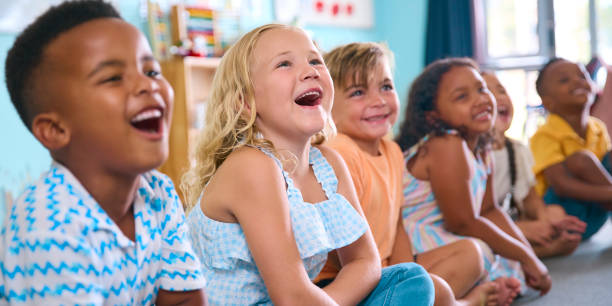 istock Line Of Smiling Primary Or Elementary School Students Sitting On Floor During Classroom Lesson 2096524281