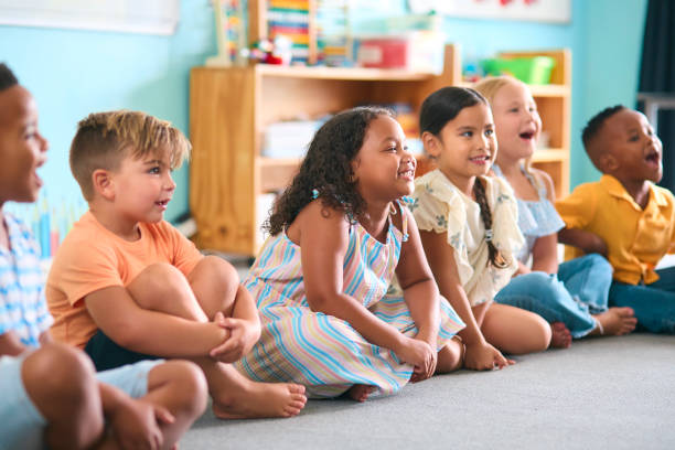 istock Line Of Smiling Primary Or Elementary School Students Sitting On Floor During Classroom Lesson 2096525345