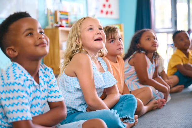 istock Line Of Smiling Primary Or Elementary School Students Sitting On Floor During Classroom Lesson 2096528605