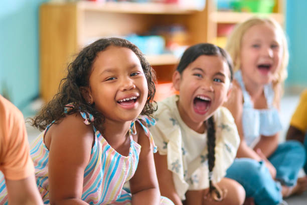 istock Line Of Smiling Primary Or Elementary School Students Sitting On Floor During Classroom Lesson 2096529748
