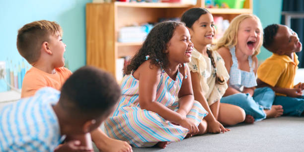 istock Line Of Smiling Primary Or Elementary School Students Sitting On Floor During Classroom Lesson 2096530963