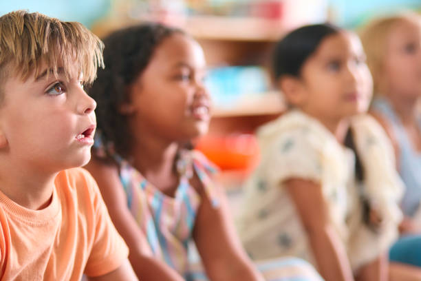 istock Line Of Smiling Primary Or Elementary School Students Sitting On Floor During Classroom Lesson 2096536466