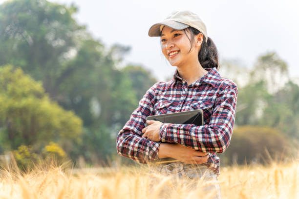 istock Happy young female farmer standing in her barley field smiling happily while holding computer tablet 2096563266