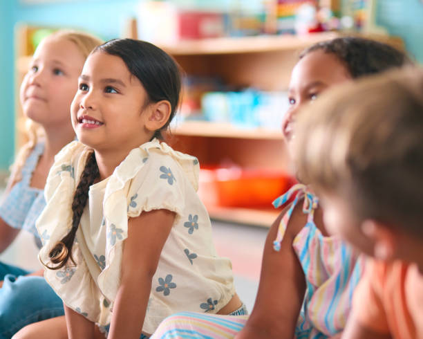 istock Line Of Smiling Primary Or Elementary School Students Sitting On Floor During Classroom Lesson 2096563823