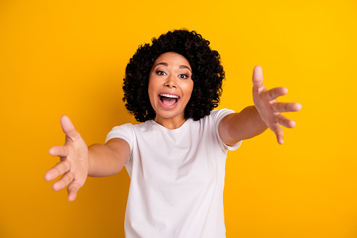 Photo of friendly funky woman wear white t-shirt rising toa open arms ready hug you isolated yellow color background.