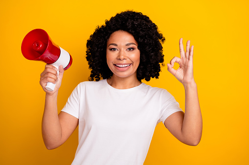 Photo of excited confident woman wear white t-shirt rising toa showing okey gesture isolated yellow color background.