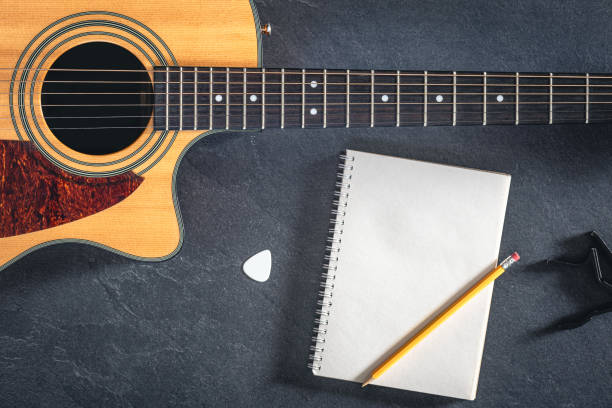 istock Acoustic guitar and notebook on a black textured background, top view. 2096607943
