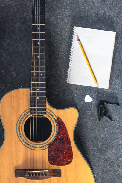 istock Acoustic guitar and notebook on a black textured background, top view. 2096607946